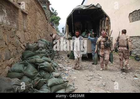 Tschechische Soldaten und Offiziere der afghanischen Uniform Polizei entladen Sandsäcke aus einem LKW. Stockfoto