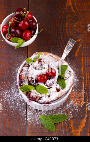 Französische Clafoutis mit Kirsche in Keramik Förmchen auf rustikalen Holztisch Stockfoto