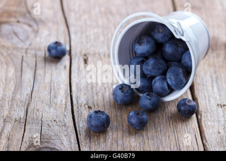 Reife Heidelbeeren in einer kleinen weißen Eimer auf rustikalen Holzbrett, Makro, selektiven Fokus Stockfoto