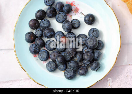 Frisch gepflückten Heidelbeeren in Holzschale. Saftige und frische Heidelbeeren mit grünen Blättern auf rustikalen Tisch. Stockfoto