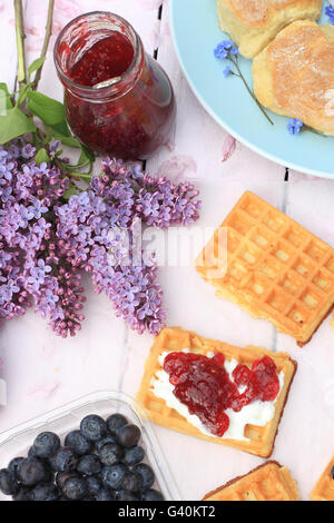 Frisch gebackene belgischen Waffeln auf romantische Holztisch mit lila Blumen Stockfoto