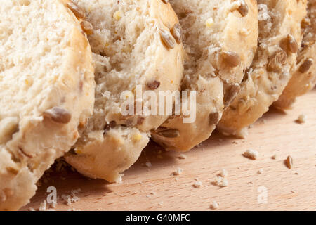 Nahaufnahme Schuss frisch geschnittenen Honig und Sonnenblumen ausgesät Brot Verlegung auf ein Schneidbrett aus Holz Stockfoto