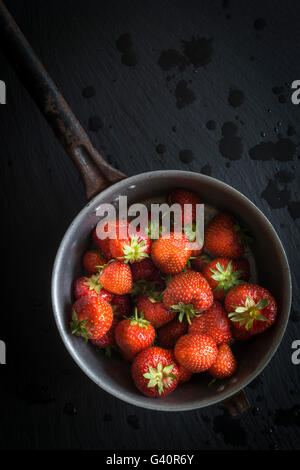 Erdbeeren in Vintage Sieb auf schwarzem Schiefer. Ansicht von oben Stockfoto