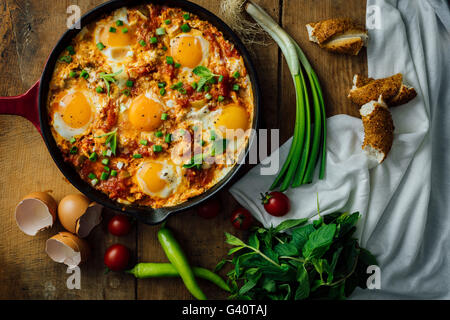 Eiern mit Tomaten, Paprika und Frühlingszwiebeln in einer gusseisernen Pfanne gekocht. Stockfoto