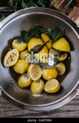 Eine Schüssel mit Zitronen mit Zucker, Rosmarin und Minze gemischt werden aus der Ansicht von oben fotografiert. Stockfoto