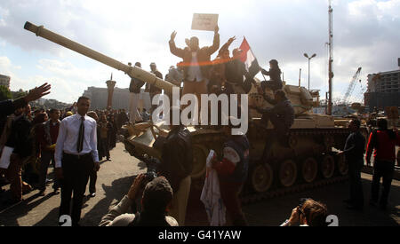 Demonstranten klettern auf einen Panzer in der Nähe des Tahrir-Platzes in Kairo, Ägypten, während die Massenproteste gegen die drei Jahrzehnte währende Herrschaft von Präsident Hosni Mubarak im ganzen Land andauern. Stockfoto