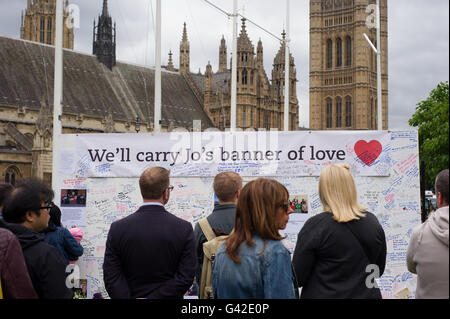 London, England, Vereinigtes Königreich. 18. Juni 2016. Floral Tribute legten außerhalb Westminster als eine Hommage an Labour MP Jo Cox starb nachdem er außerhalb ihrem Wahlkreis im Birstal angegriffen. Menschen nicht mehr um zu betrachten, ein Brett, die besagt "Wir Jo es Banner der Liebe trage" platziert wurde. Die Leute schrieben mehrere Nachrichten an der Wand. Bildnachweis: Andrew Steven Graham/Alamy Live-Nachrichten Stockfoto