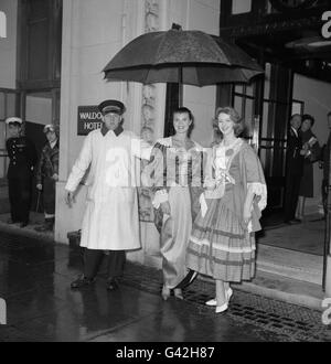 Unter einem Regenschirm in farbenfrohen Kostümen schützen Hilda Fairclough (Miss UK) und Irene Kane (Miss Ireland), zwei Teilnehmer des Miss World-Wettbewerbs, der in London stattfindet, Stockfoto