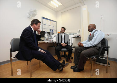 Premierminister David Cameron (links) chattet mit Dr. Usman Quraishi (Mitte) und einem Patienten während eines Besuchs im St. Charles Centre for Health and Wellbeing in Kensington. Stockfoto