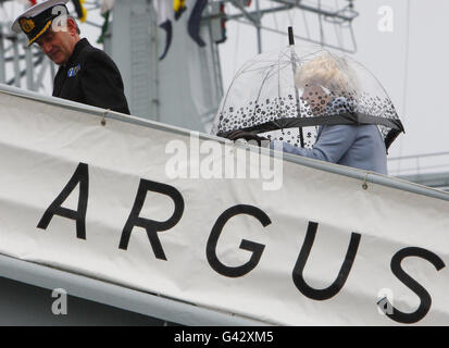 Die Herzogin von Cornwall untersteht einem Regenschirm, während sie Kapitän Paul Kehoe entlang der Gangway folgt, nach ihrer Ankunft für eine Tour an Bord des Royal Fleet Auxiliary Ship, RFA Argus, um die Einrichtungen zu sehen und sich mit dem Personal des Krankenhausschiffes zu treffen, Am Royal Naval Base in Portsmouth. Stockfoto