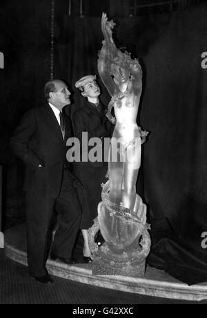 Dr. Arthur Fleischmann ARBS, der in Tschechien geborene australische Bildhauer und seine Kunststudentin Cecile im Australia House, London, mit seinem neuen Werk „The Queen of the Seas“ (Geburt der Aphrodite), einer 7 m langen Figur, die aus einem massiven, halbtonnenschweren Block aus Plexiglas geschnitzt wurde. Es ist das größte Stück Skulptur, das jemals in das neue Material geschnitzt wurde. Die Figur soll in der Embarkation Hall des neuen Pacific Steam Navigation Liners Reina del Mar platziert werden, der jetzt in Harland und Wolff's Werft in Belfast eingebaut wird. Stockfoto