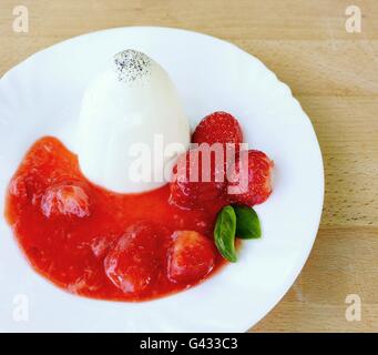 Panna Cotta mit Erdbeeren, Erdbeeren Sauce und Basilikum Blätter auf weißen Teller. Stockfoto