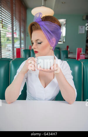 1960er Jahre schauen Pin-up Girl in einem American Diner hält eine Kaffeetasse Stockfoto