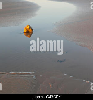 Eine einsame Stein steht allein am Strand wie die Flut fällt Stockfoto