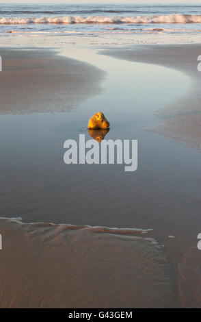 Eine einsame Stein steht allein am Strand wie die Flut fällt Stockfoto