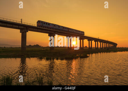 Ein Zug ist die Brücke am Pa Sak Jolasid Damm, Thailand im Sonnenuntergang Stockfoto