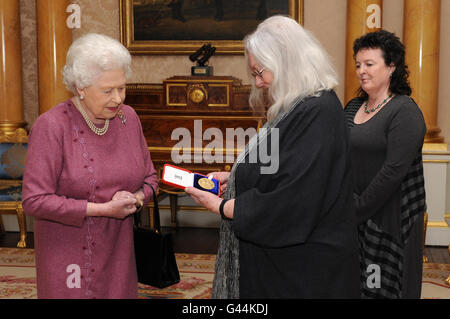 Die britische Königin Elizabeth II. Überreicht der Dichterin Gillian Clarke (Mitte) ihre Goldmedaille für Poesie, die von der Dichterin Carol Ann Duffy (rechts) im Buckingham Palace verfolgt wird. Stockfoto
