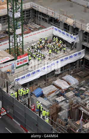 Mehr als 40 Bläser- und Schlagzeugmusiker der Guildhall School of Music and Drama führen auf dem Boden des neuen Konzertsaals der Schule, der derzeit im Milton Court in London entwickelt wird, einen "Hardhat Prom" auf. Stockfoto