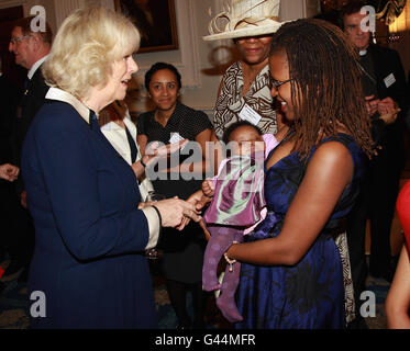 Camilla, Herzogin von Cornwall, trifft Judith Craig und das Baby Afrykah-Amaya Morency-Nalus von den Vereinigten Haitianern in der britischen Gruppe während eines Empfangs des Roten Kreuzes im Mansion House, London, um den Freiwilligen und Spendern zu danken, die nach der Katastrophe vom 2010. Januar beim Wiederaufbau des Landes mithelfen. Stockfoto