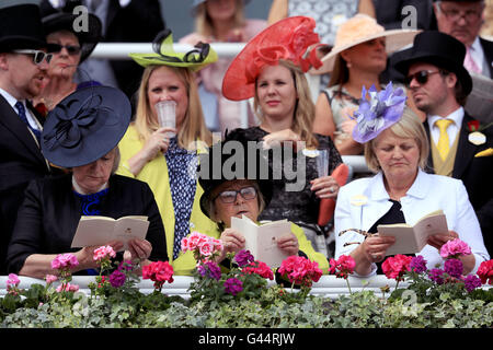 Racegoers lesen Sie im offiziellen Programm der Royal Ascot tagsüber vier Royal Ascot 2016 auf dem Ascot Racecourse. Stockfoto