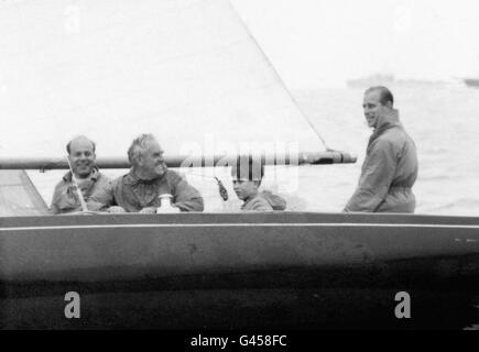 Prinz Charles an Bord der Dragon Class Yacht Bluebottle, mit seinem Vater, dem Duke of Edinburgh, Leutnant-Commander Alastair Easton, extrem links, und Segler Uffa Fox. Stockfoto