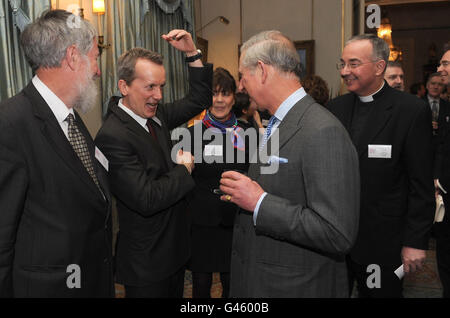 Prinz Charles spricht mit Frank Skinner (2. Links), während er einen Empfang im Clarence House veranstaltet, um den 400. Jahrestag der King James Bible in London zu feiern. Stockfoto