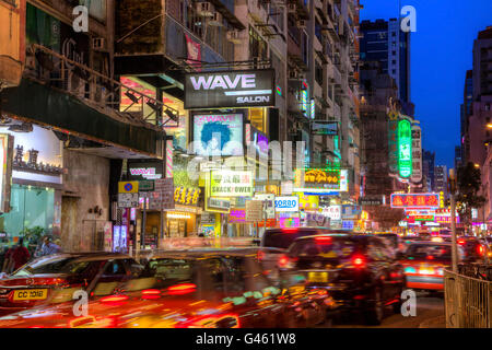 HONG KONG - 27. Juli 2015: Autos Streifen entlang der belebten Sai Yeung Choi Street in Mongkok, Kowloon, als Leuchten bunte Plakatwände. Stockfoto