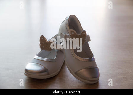 Paar weiße Schuhe für Mädchen mit Schmetterling - geformte Ornamente auf Holzboden Stockfoto