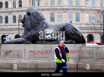 Ein Arbeiter passiert einen der Löwen auf dem Trafalgar Square in London, bedeckt mit Graffiti, nachdem Aktivisten gestern Abend nach der TUC-Kundgebung im Hyde Park mit der Bereitschaftspolizei zusammenprallten, die zuvor friedlich verstorben war. Stockfoto