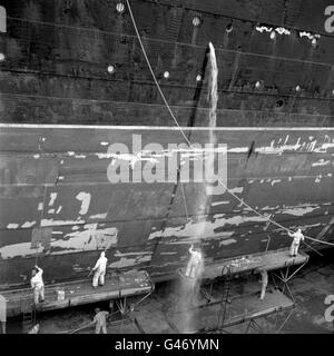 Eine Flut von Wasser kommt zu einem Arbeiter, der am Rumpf des Liners „RMS Queen Elizabeth“ im King George V Dry Dock in Southampton arbeitete. Stockfoto