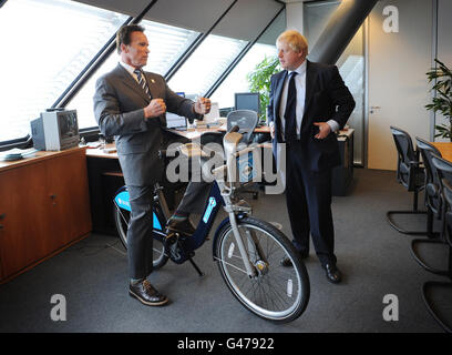 Der Bürgermeister von London, Boris Johnson, zeigt den ehemaligen Gouverneur von Kalifornien, Arnold Schwarzenegger (links), eines seiner "Boris-Fahrräder" in seinem Büro im Londoner City Hall. Stockfoto