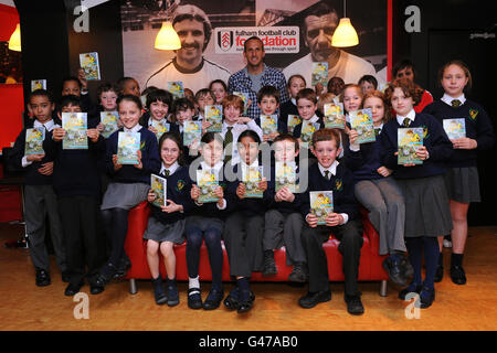 Fußball - Fulham Foundation Event - Craven Cottage. Fulhams Mark Schwarzer posiert für ein Foto mit Kindern, die sein Buch lesen Stockfoto