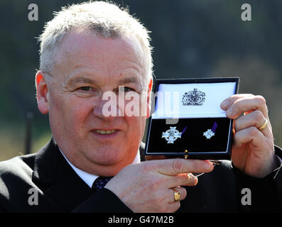 Johnny Caie, Bruder des Troopers Ian Caie, der im August 1972 in Nordirland während seines Diensts bei der Royal Scots Dragoon Guards getötet wurde, hält das Elizabeth Cross, das ihm und seiner Familie im Namen der britischen Königin Elizabeth II. Von Brigadier Simon Allen überreicht wurde, In Anerkennung des Opfers, das der Trooper Ian Caie gemacht hat. Am Kriegsdenkmal der Royal Scots Grays in den Princes Street Gardens, wo sich eine Inschrift des Namens Ian Caie befindet. Stockfoto