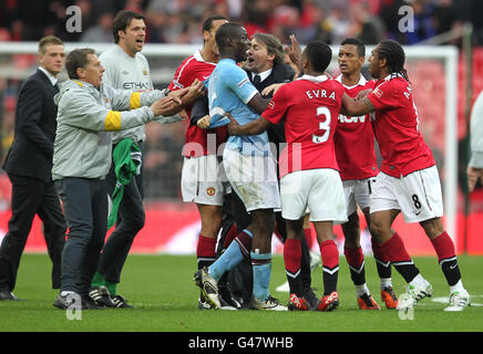 Manchester City Manager Roberto Mancini kommt seinem Spieler Mario Balotelli zu Hilfe, als die Manchester United-Spieler Rio Ferdinand, Patrice Evra, Nani und Anderson ihre Punkte auf den Weg bringen Stockfoto