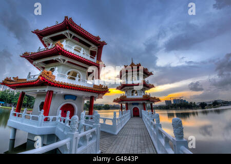 Sonnenuntergang über der Twin Pagoden auf einem Teich im chinesischen Garten, einen öffentlichen Park in Singapur. Der Garten ist nach der chinesischen Im modelliert. Stockfoto