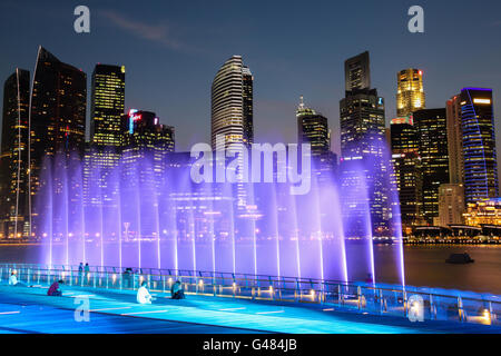 Singapur - 7. APRIL: A Menschenmenge versammelt, beleuchteten Wasserfontänen Skywards auf die Marina Bay in Singapur in der Abenddämmerung schießen zu sehen Stockfoto