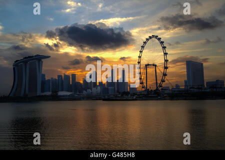 Ein Goldener Sonnenuntergang über Singapurs Skyline schafft eine interessante Silhouette der Marina Bay. Stockfoto