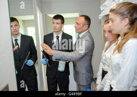 Auszubildende, die Reinigung eines Spiegels unter Aufsicht Stockfoto