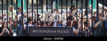 Die Zuschauer beobachten die Wachablösung durch das Geländer des Buckingham Palace in London. Stockfoto