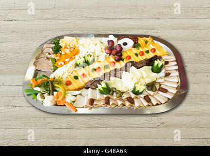 Kalte Platte mit Schinken, Käse, Oliven, Wurst, frisches Obst und Gemüse auf Holztisch Stockfoto