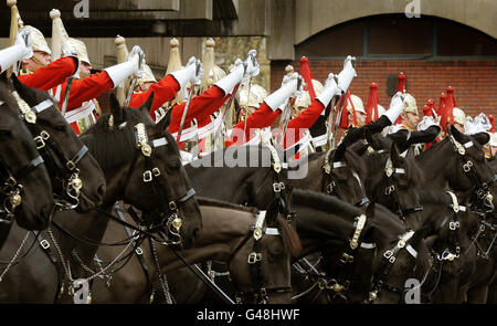 Troopers der Rettungsschwimmer (goldene Kopfbedeckung) und der Blues and Royals (rote Kopfbedeckung), Teil des Household Cavalry Mounted Regiment, ziehen ihre Schwerter in den Hyde Park Barracks, Knightsbridge, während einer Probe für die Überprüfung des Generalmajors am 21. April, Welche bestimmen wird, ob sie die Standards erfüllen, die für alle zeremoniellen Pflichten im Sommer, einschließlich der königlichen Hochzeit von Prinz William, erforderlich sind. Stockfoto