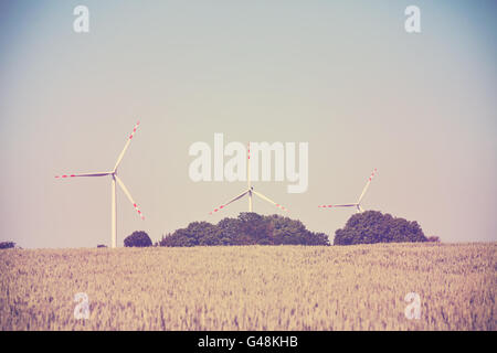 Alte Film Retro getönten Windmühlen auf einem Feld Getreide, alternative Energiekonzept. Stockfoto