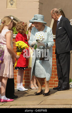 Kinder warten mit Blumen, als Königin Elizabeth II. Und der Herzog von Edinburgh den Ostermatinservice in der St. George's Chapel, Windsor Castle, verlassen. Stockfoto