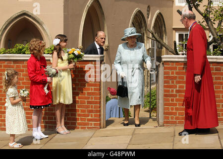 Kinder warten mit Blumen, als Königin Elizabeth II. Und der Herzog von Edinburgh den Ostermatinservice in der St. George's Chapel, Windsor Castle, verlassen, während der rechte Rev. David Conner, Dekan von Windsor, auf sie schaut. Stockfoto