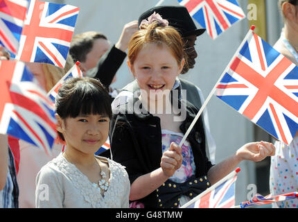 Kinder der Cottingley Primary School in Leeds winken Fahnen, als zwei ihrer Klassenkameraden eine Just-for-Fun-Hochzeit vor der königlichen Hochzeit morgen durchführen. Stockfoto