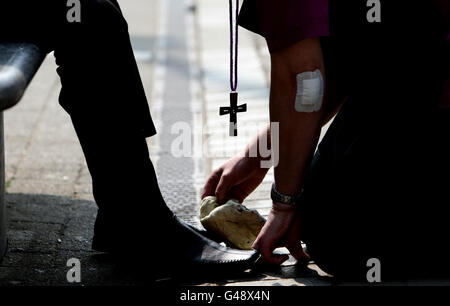 Der Bischof von Bolton, der rechte Reverend Chris Edmondson, rechts, Putzt die Schuhe eines Shoppers im Stadtzentrum von Bolton, während Bischöfe und Geistliche anbieten, die Schuhe der Menschen im ganzen Land zu reinigen, um die Menschen an die Ostergeschichte zu erinnern, die Jesus am Gründonnerstag seinen Anhängern die Füße wäscht. Stockfoto