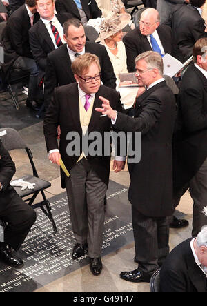 Sir Elton John (links) und sein Partner David Furnish werden zu ihren Sitzen in Westminster Abbey in London geleitet, wo Prinz William und Kate Middleton später heute heiraten werden. Stockfoto