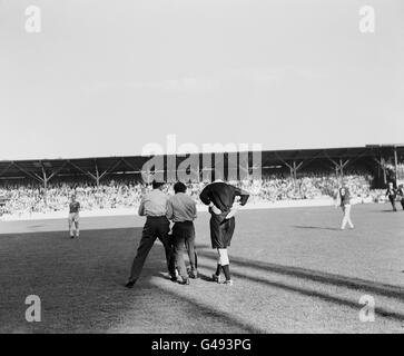 Zwei Zuschauer, die kurz davor waren, den Schiedsrichter Leslie Hamer (versteckt) vor dem Linienrichter anzugreifen, nachdem Lawrence Leslie, Torhüter von West Ham United, auf einer Bahre abtransportiert wurde. Stockfoto