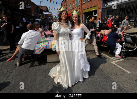 Danielle Barnes-Rouf (links) und Hannah Thomas tragen Hochzeitskleider, um die Hochzeit von William und Kate auf einer Party in der Thomas Street in Manchester zu feiern. Stockfoto