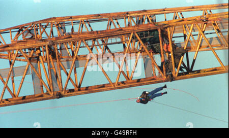 Ein Protestor (links) wird vom riesigen Kran heruntergelassen, der heute (Dienstag) für die Installation der 12 Masten verwendet wird, die zur Unterstützung der Konstruktion des Millennium Dome in Greenwich benötigt werden. Neun Aktivisten, die sich selbst Time Bomb nannten, ketteten sich an den 350 Meter langen Kran und entrollten ein Transparent mit der Aufschrift: Domesday Dome. Foto von David Giles. Siehe PA Story MILLENNIUM Protest. Stockfoto